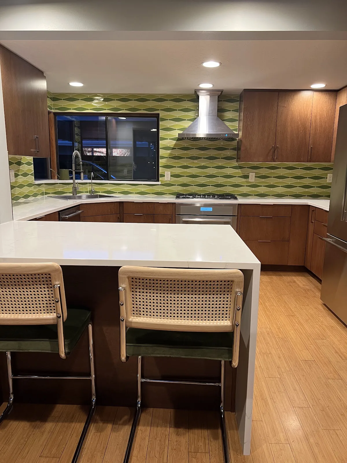 Mid-century Bellingham kitchen with wood cabinetry, quartz waterfall peninsula and green tile backsplash in Bellingham, WA — Living By Design