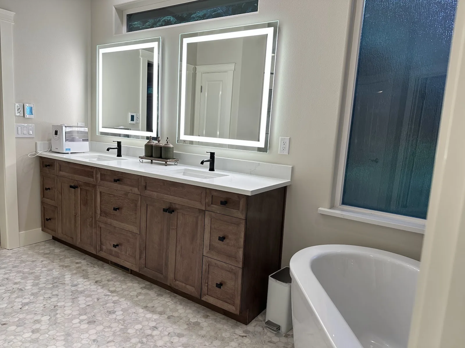 Blaine primary bathroom with navy wall, marble-look tile, wood vanity and freestanding tub in Blaine, WA — Living By Design (4)